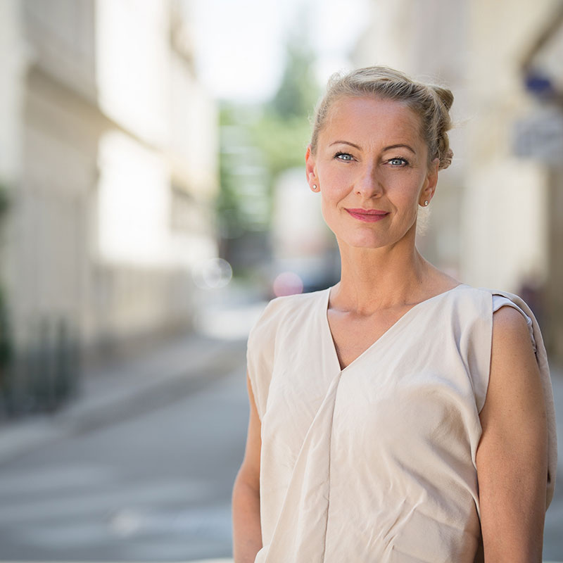 Petranna Bayerl Abbildung von Petranna Bayerl, blonde, aufgesteckte Haare, blaue Augen, weißes Shirt.
